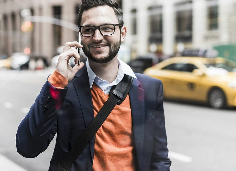 Well-dressed man holding cell phone on street in New York City