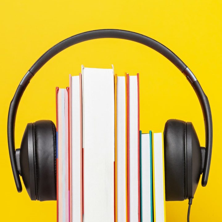 stack of books held together by over-ear headphones, audiobook