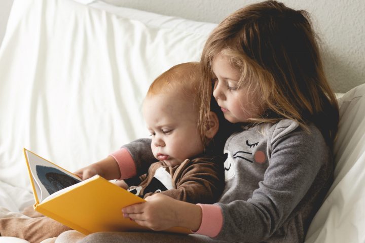 little girl and baby brother reading a book