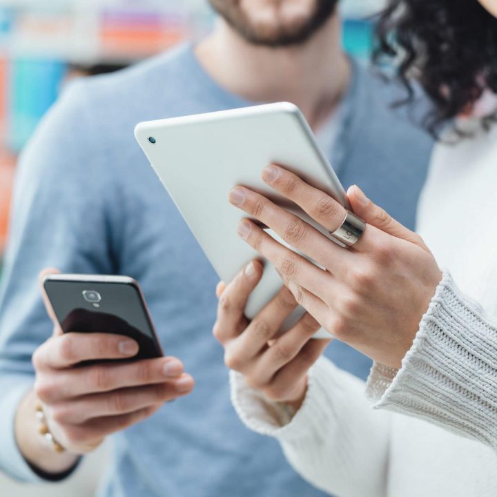 man and woman looking at phone and tablet devices